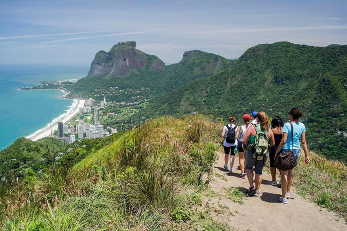 a group of people walking up a hill overlooking the ocean