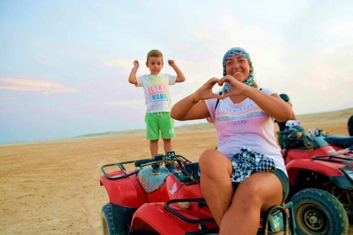 seorang wanita dan seorang budak lelaki duduk di atas kereta empat roda di padang pasir