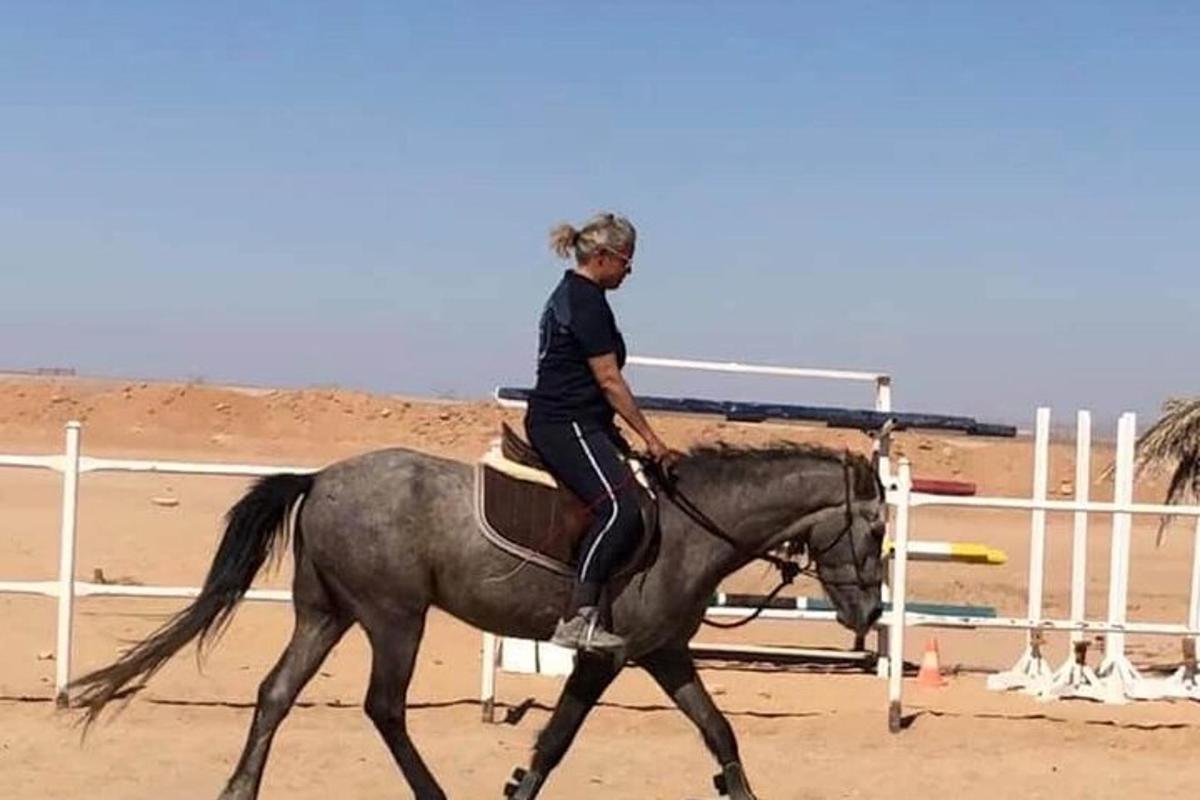 μια γυναίκα που καβαλάει ένα άλογο στην παραλία