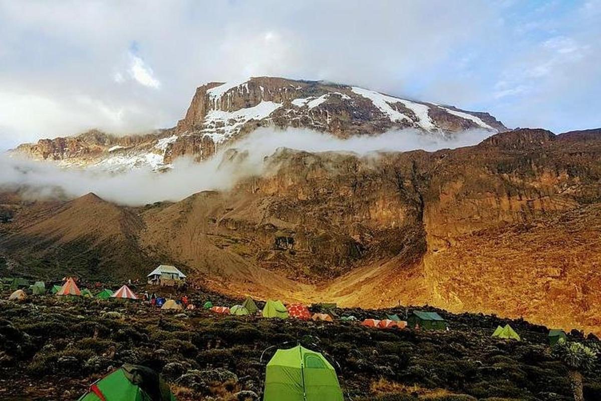 isang bundok na may mga tolda at isang bundok na natatakpan ng niyebe
