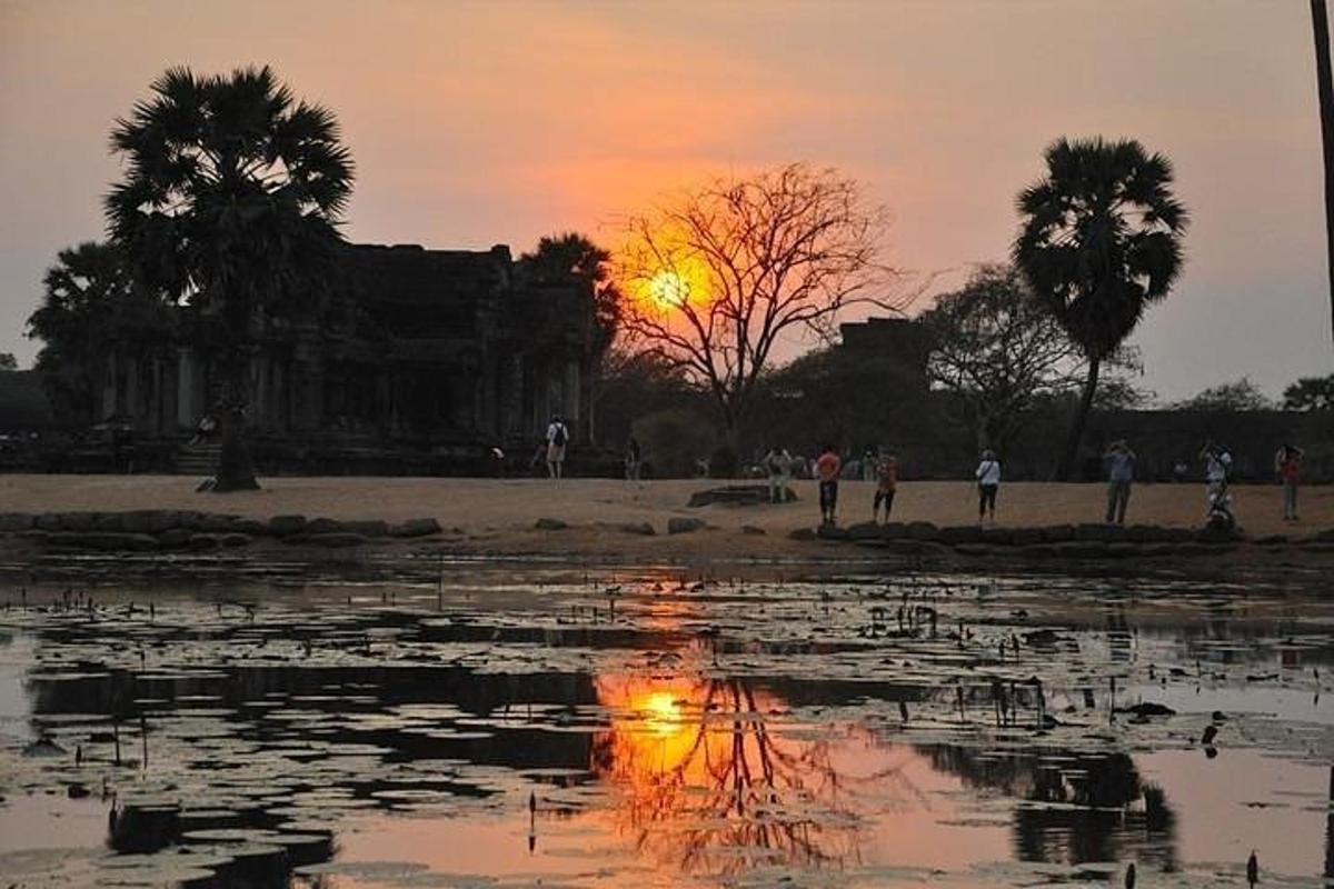 un tramonto su uno specchio d'acqua con persone che camminano