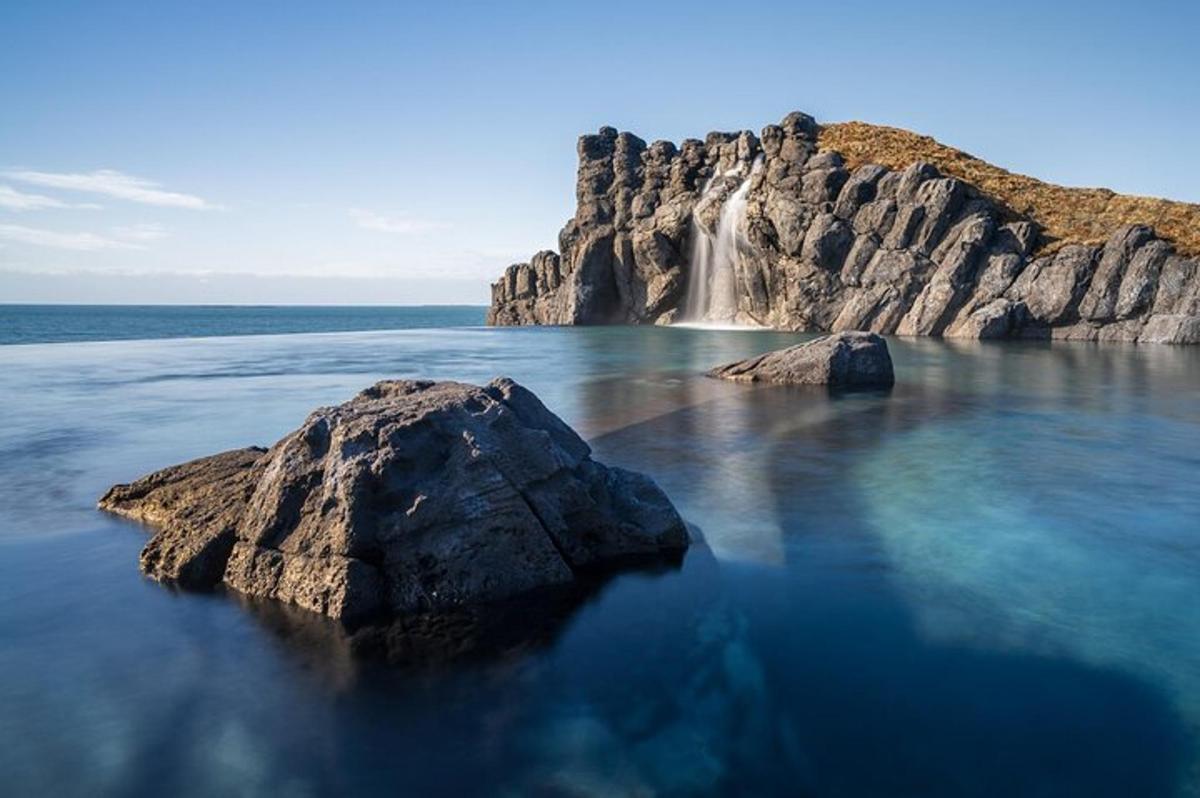 una cascata nell'oceano con una roccia nell'acqua