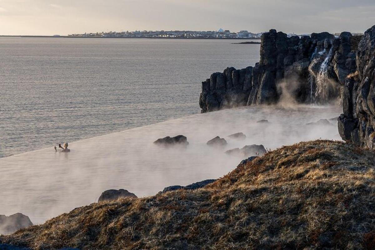un gruppo di persone in piedi nell'acqua accanto a una scogliera