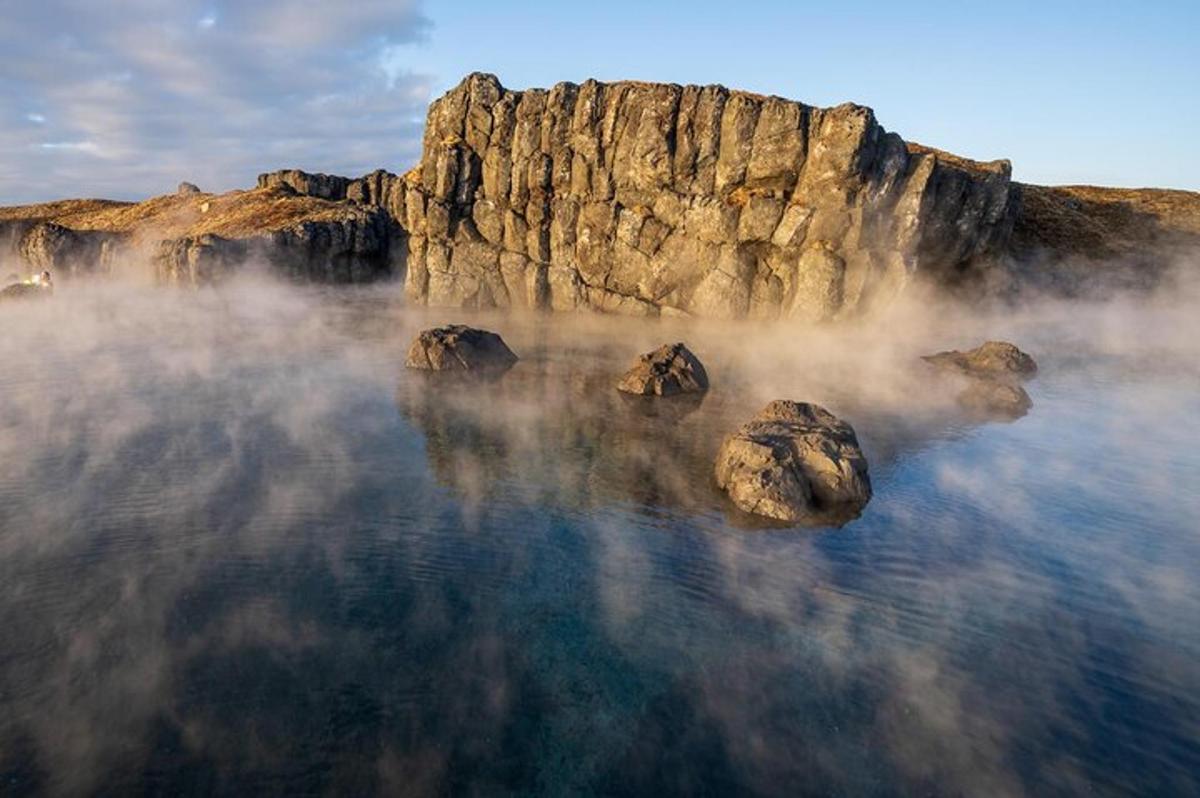 a body of water with rocks in front of a mountain