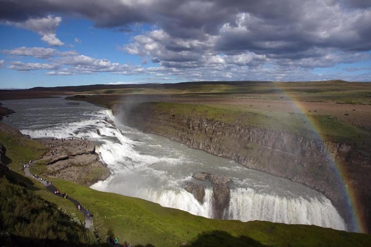 a rainbow over a waterfall next to a river