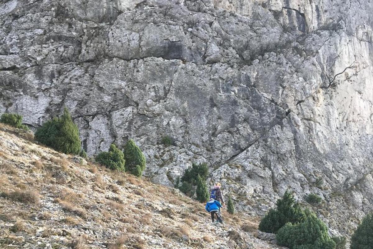 ένα άτομο που στέκεται σε έναν λόφο κοντά σε ένα βραχώδες βουνό