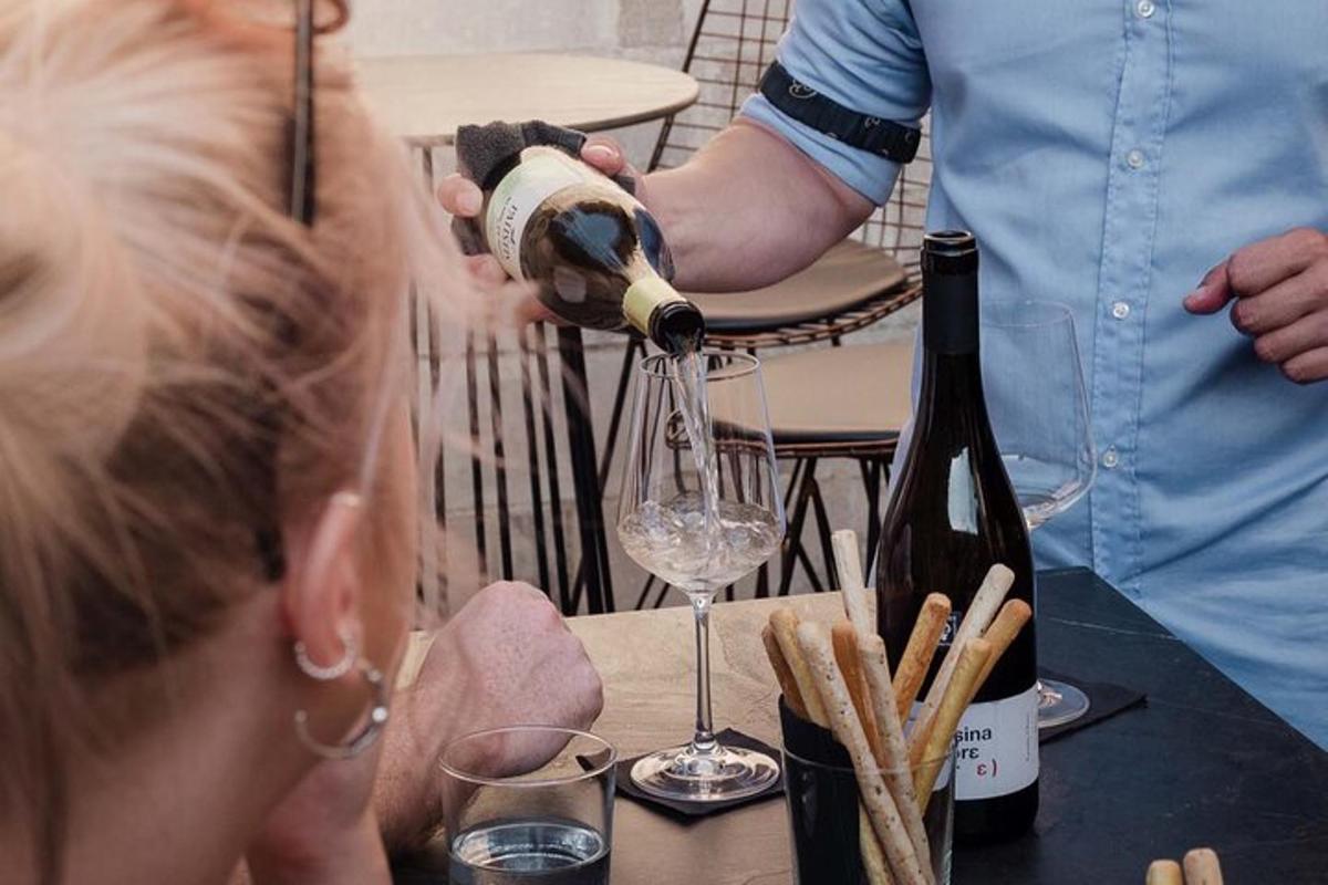 uma mulher despejando uma garrafa de vinho em uma taça de vinho