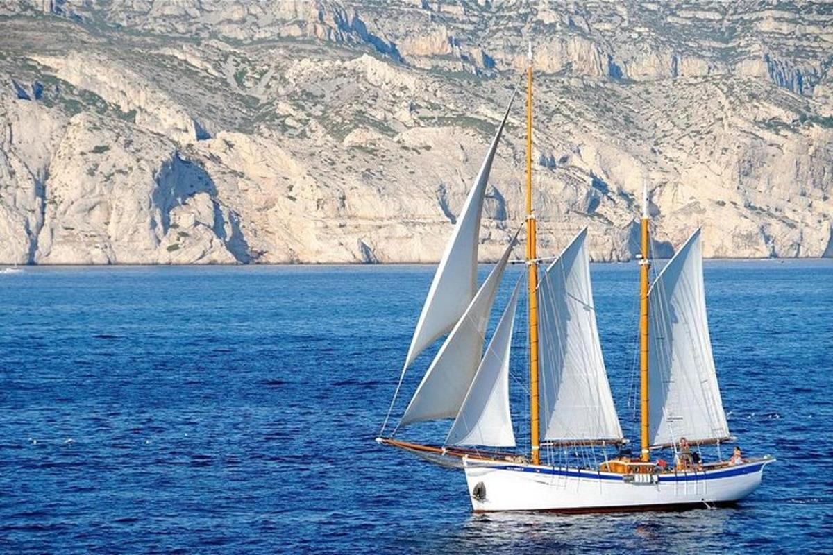 μια βάρκα με άσπρα πανιά σε ένα μεγάλο υδάτινο σώμα