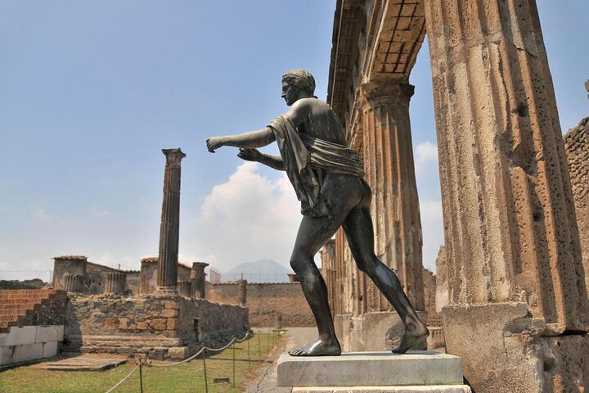 Una estatua de un hombre de pie junto a una columna.