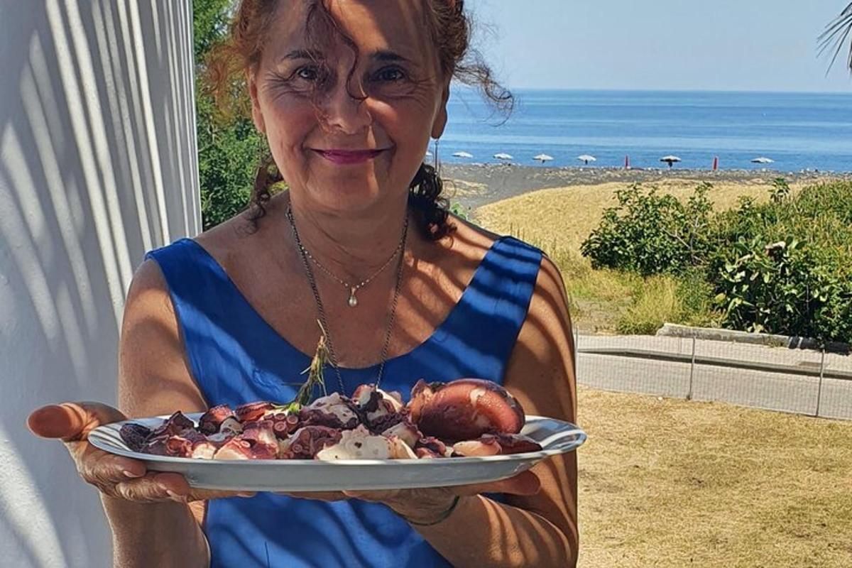 en kvinde, der holder en tallerken med mad med havet i baggrunden