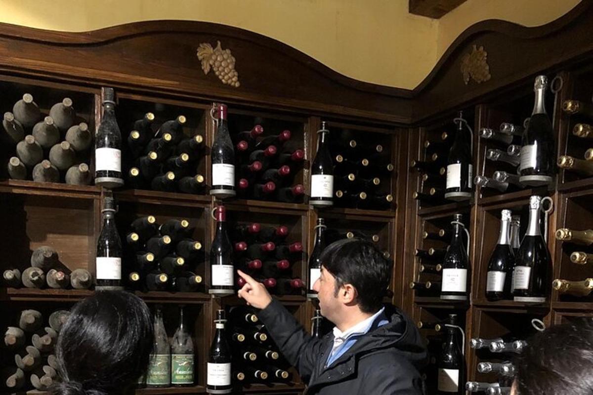 un uomo in piedi davanti a uno scaffale di bottiglie di vino
