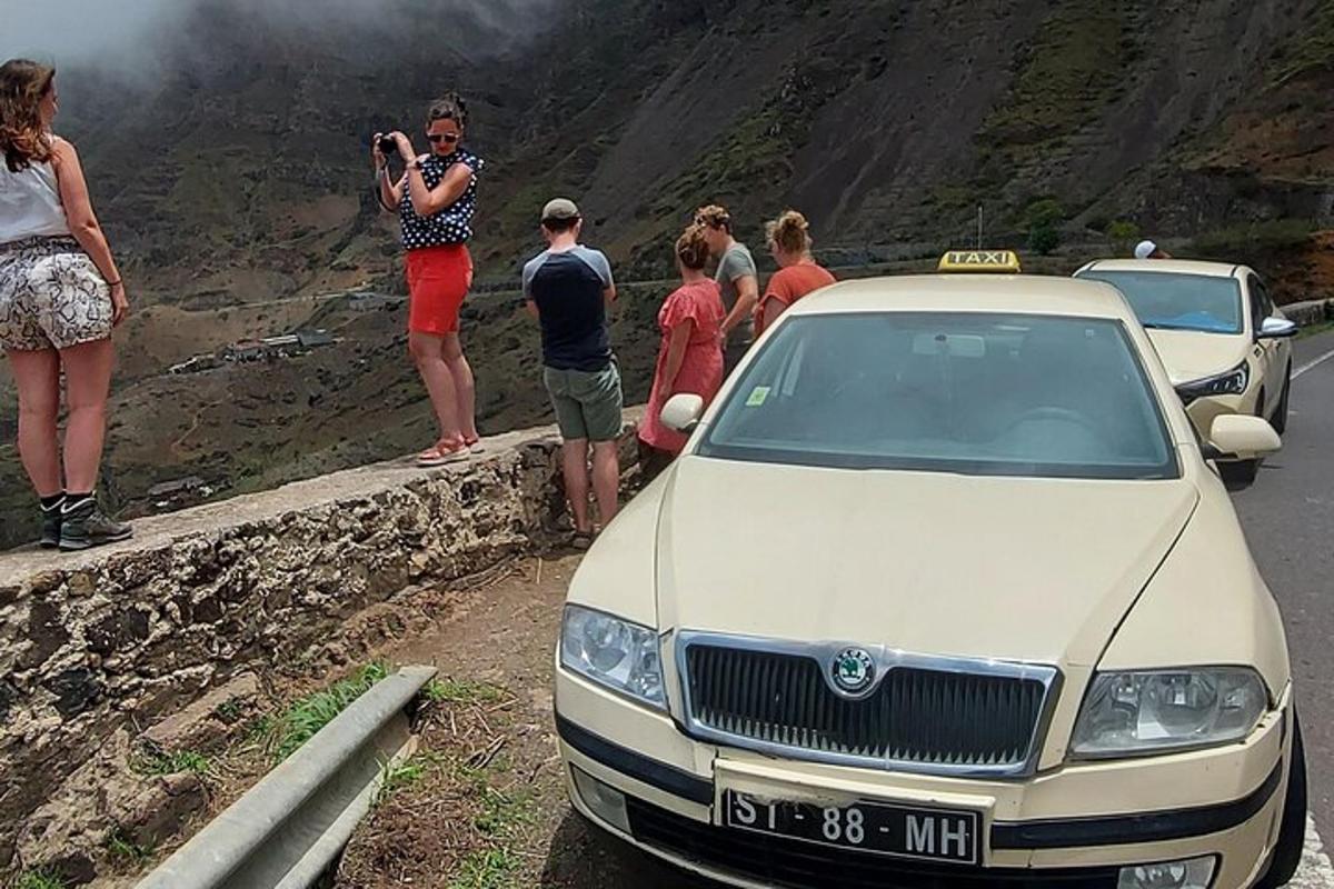 a group of people standing on a wall next to a car