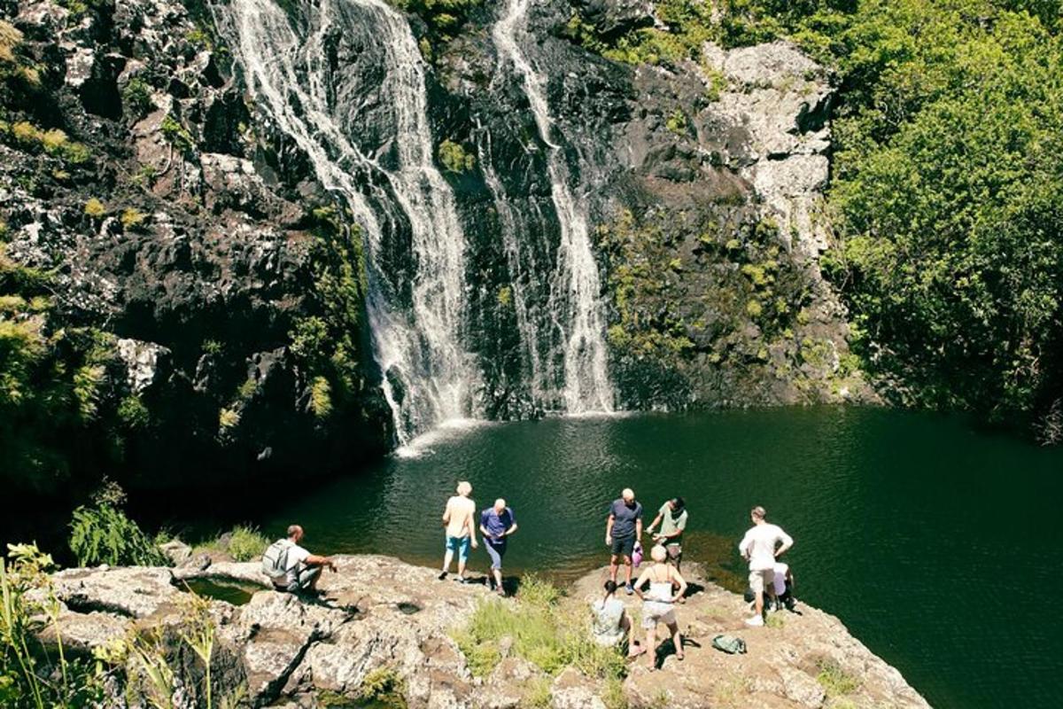 un grup de persones dretes al voltant d'un llac davant d'una cascada