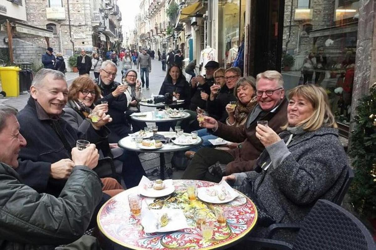 μια ομάδα ανθρώπων που κάθονται σε τραπέζια τρώγοντας φαγητό