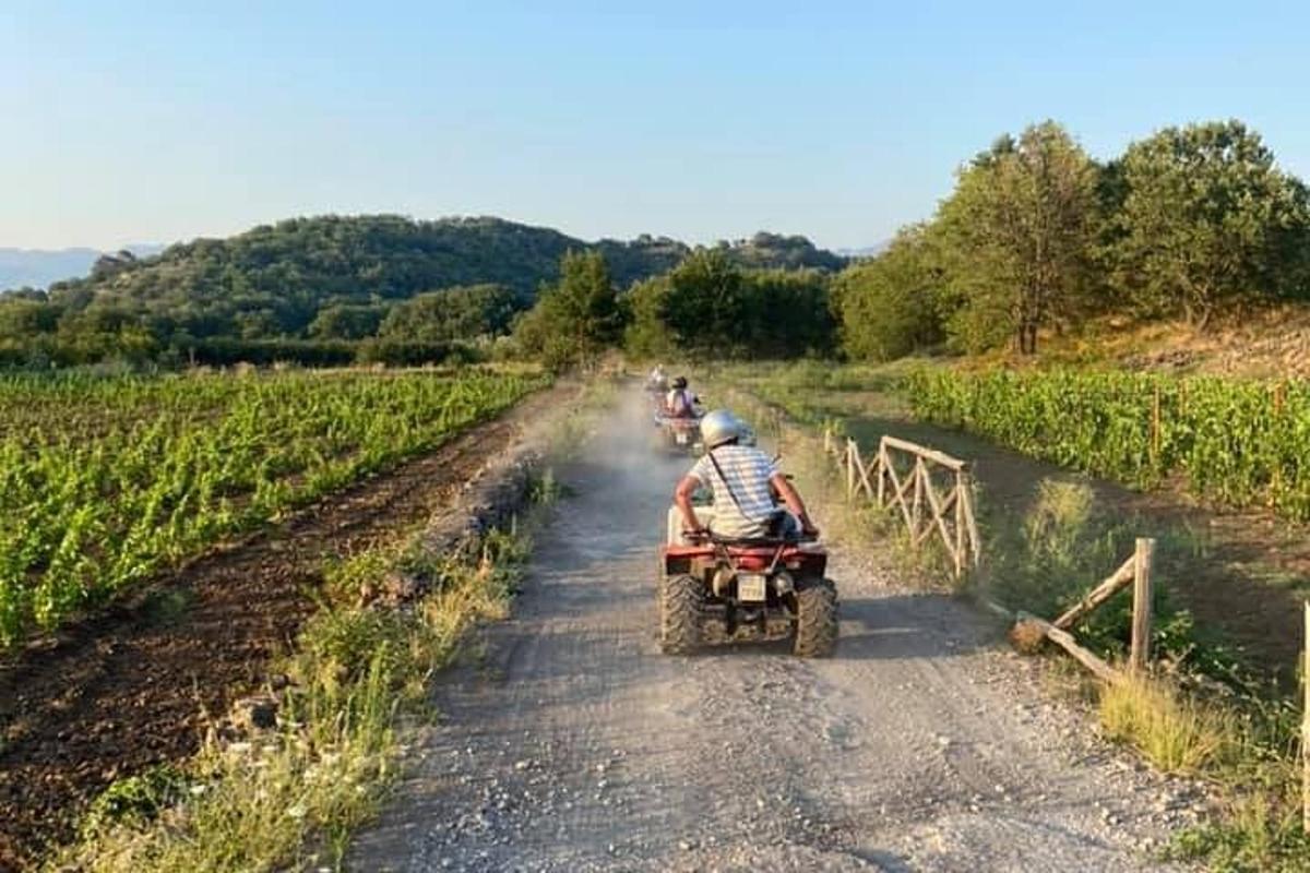 skupina ljudi, ki se vozijo na štirikolesniku po makadamski cesti