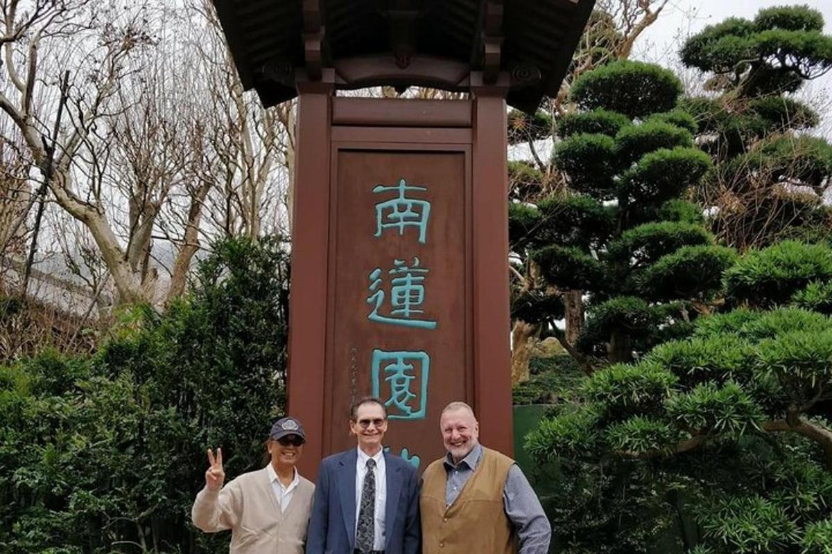 isang grupo ng tatlong lalaki na nakatayo sa harap ng isang monumento
