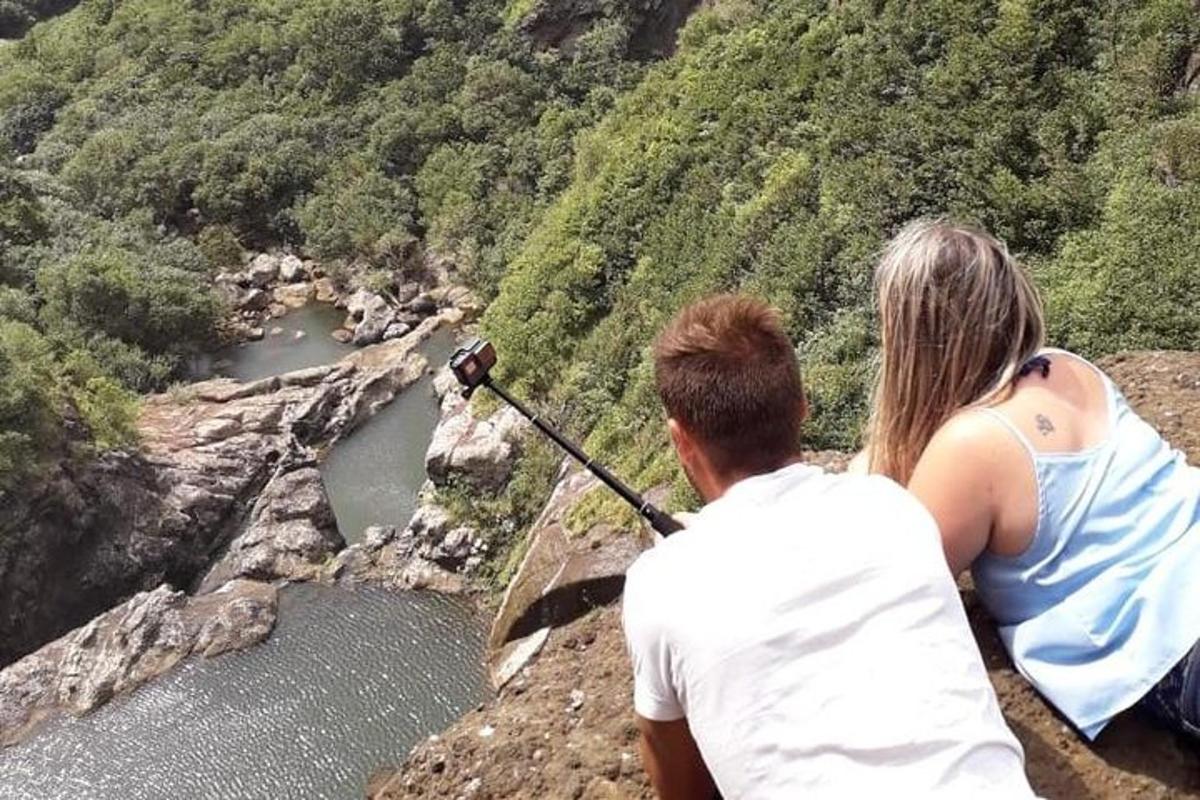 um homem e uma mulher sentados em um penhasco olhando para um rio