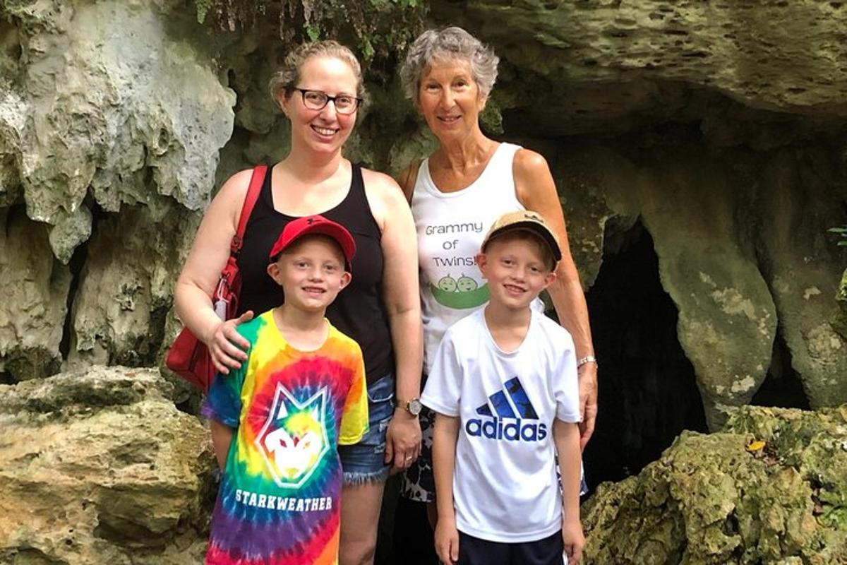 a woman and two children standing in front of a cave