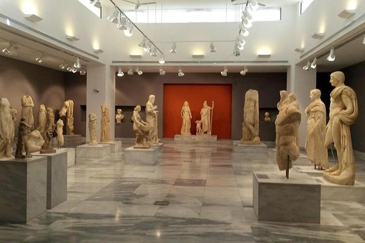 Una sala de museo con un montón de estatuas en exhibición.