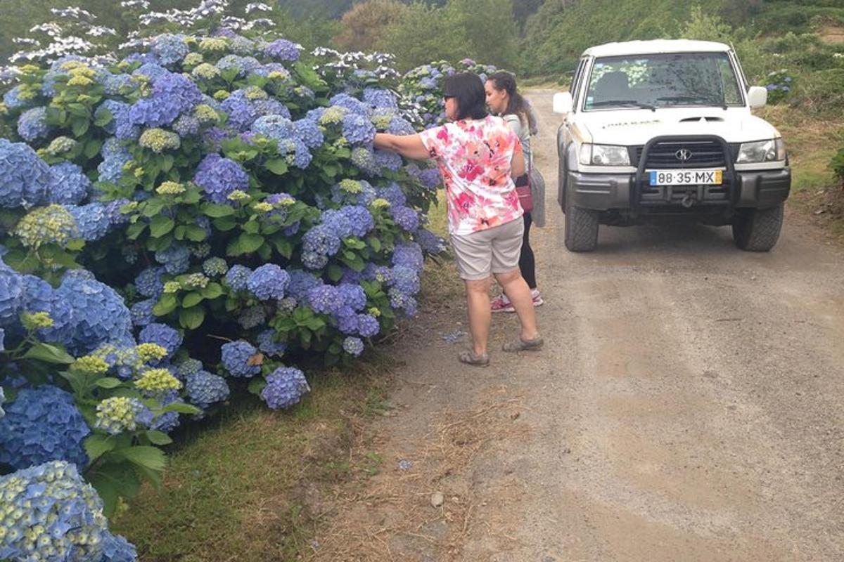 двоје људи стоје испред букета љубичастог цвећа