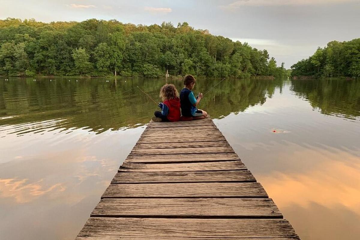 two children sitting on a wooden pier on a lake