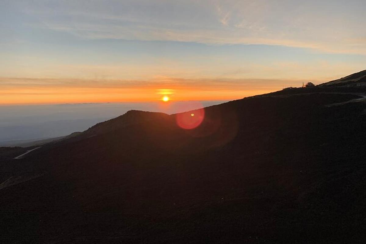 a sunset on top of a mountain with the sun setting