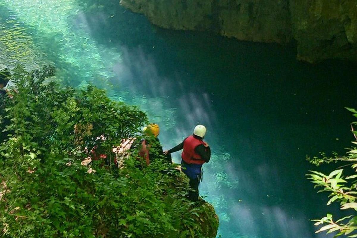un home dret en un penya-segat a prop d'una cascada