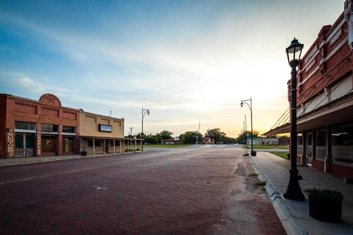 an empty street in a town with buildings and a street light
