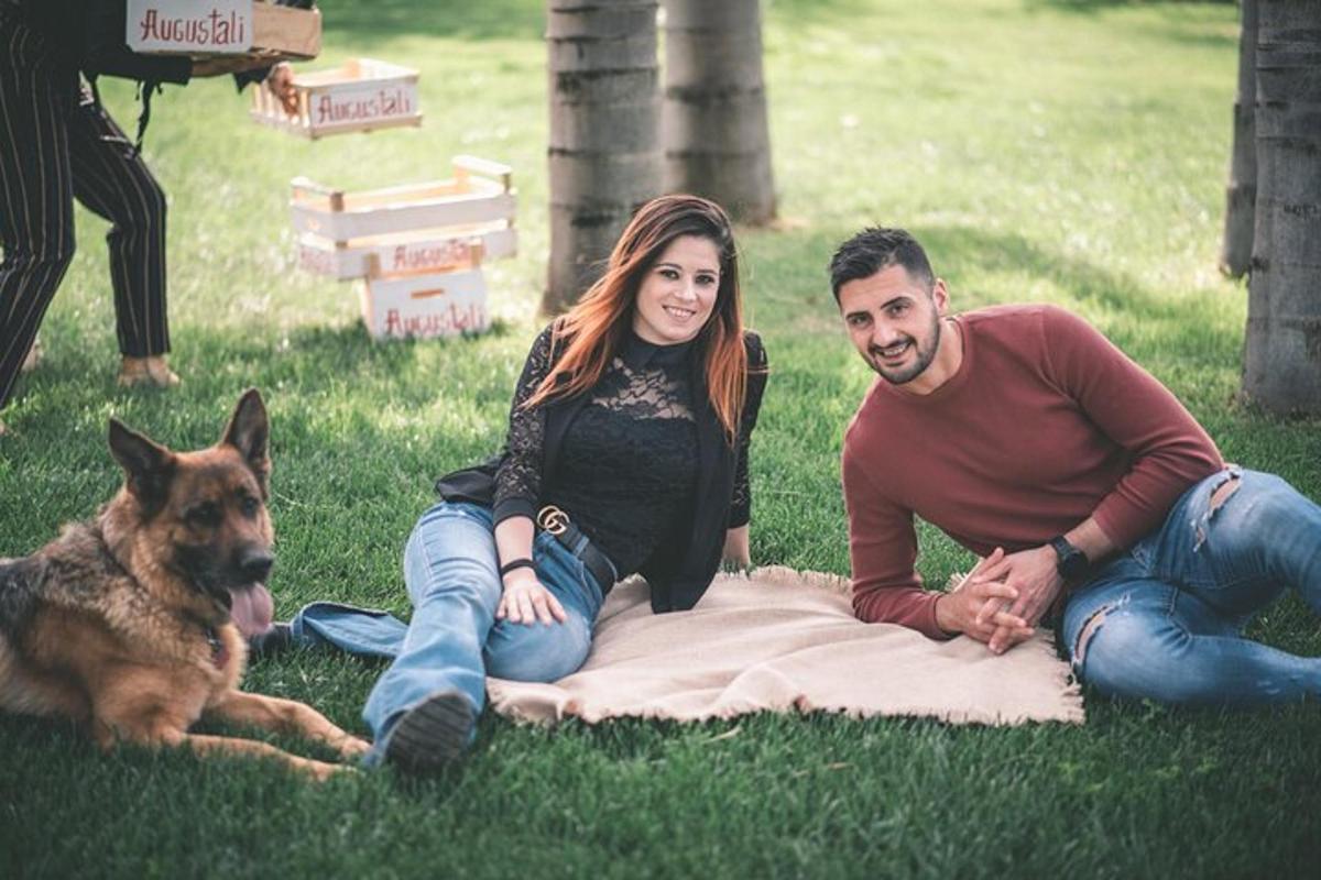 Un hombre y una mujer sentados en el césped con un perro.