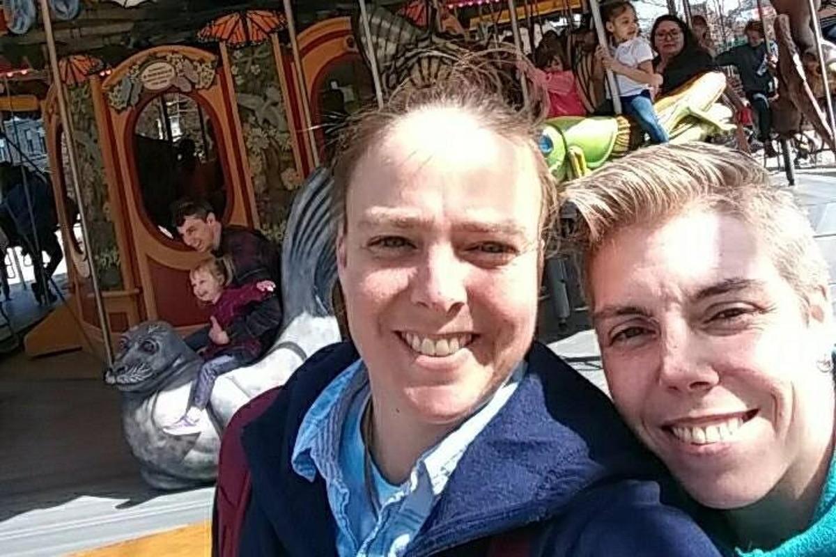 a man and woman posing for a picture at a carousel