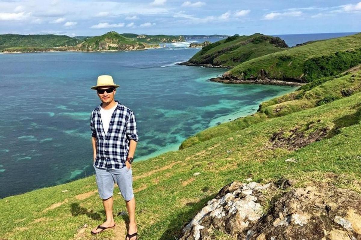 a man standing on a hill near the ocean
