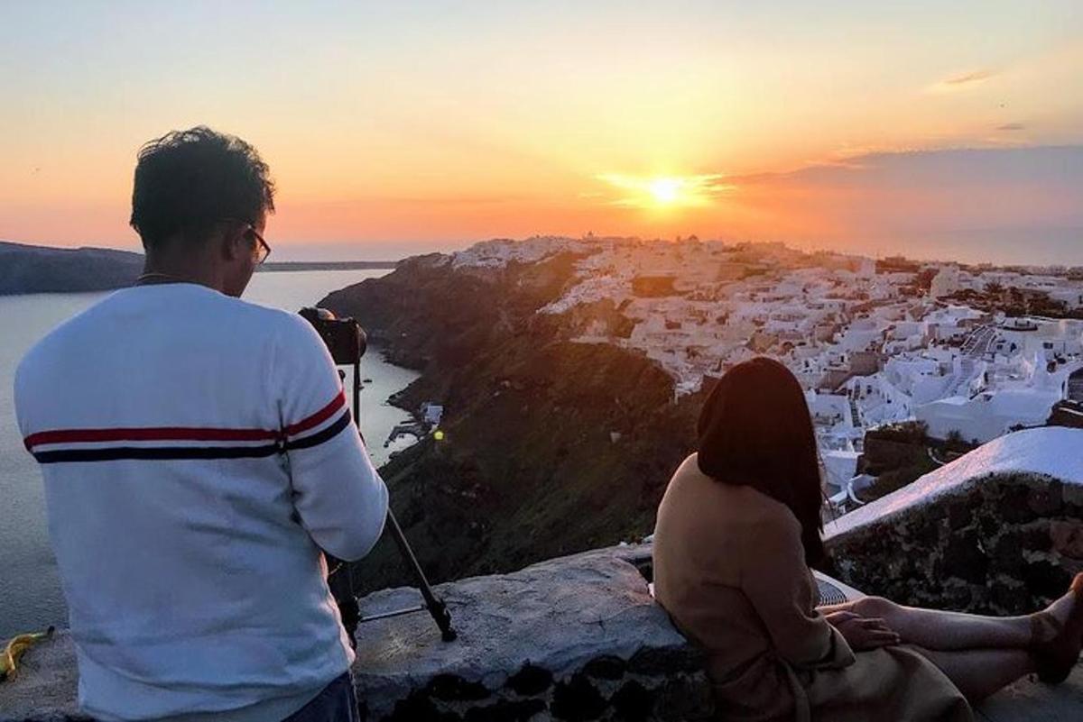 vīrietis un sieviete sēž uz klints un vēro saulrietu