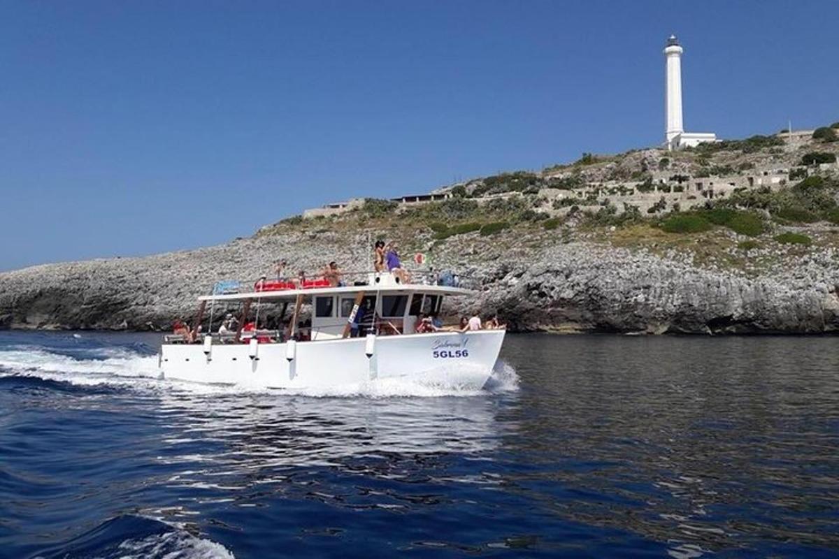 a white boat on the water with a lighthouse in the background