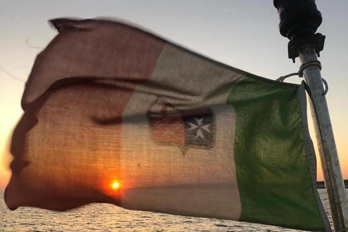 a flag on a pole with the sunset in the background