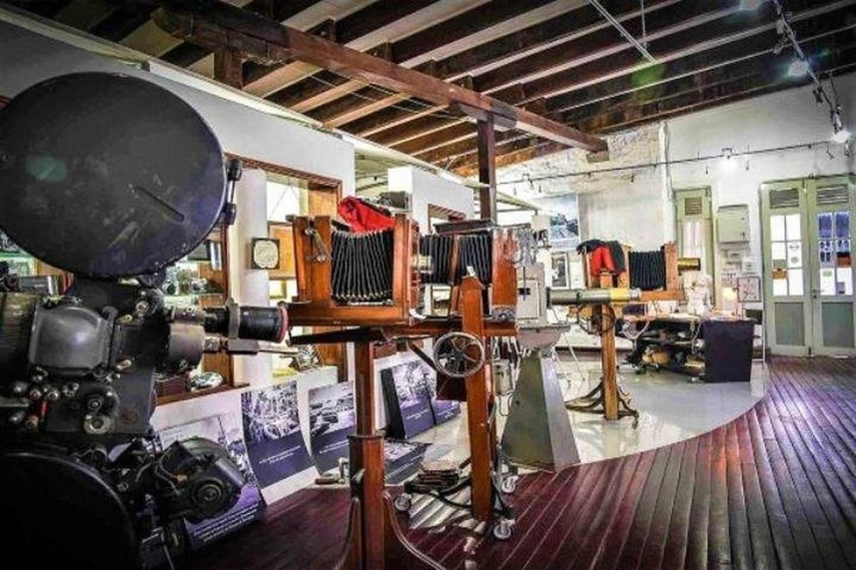 uma câmera em um tripé em uma sala com muitas roupas