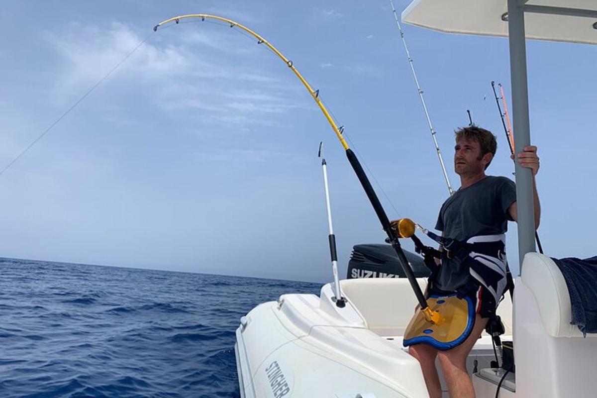 a man sitting on a boat holding a fishing rod