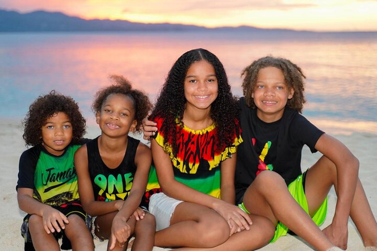 Una mujer y tres niños sentados en la playa