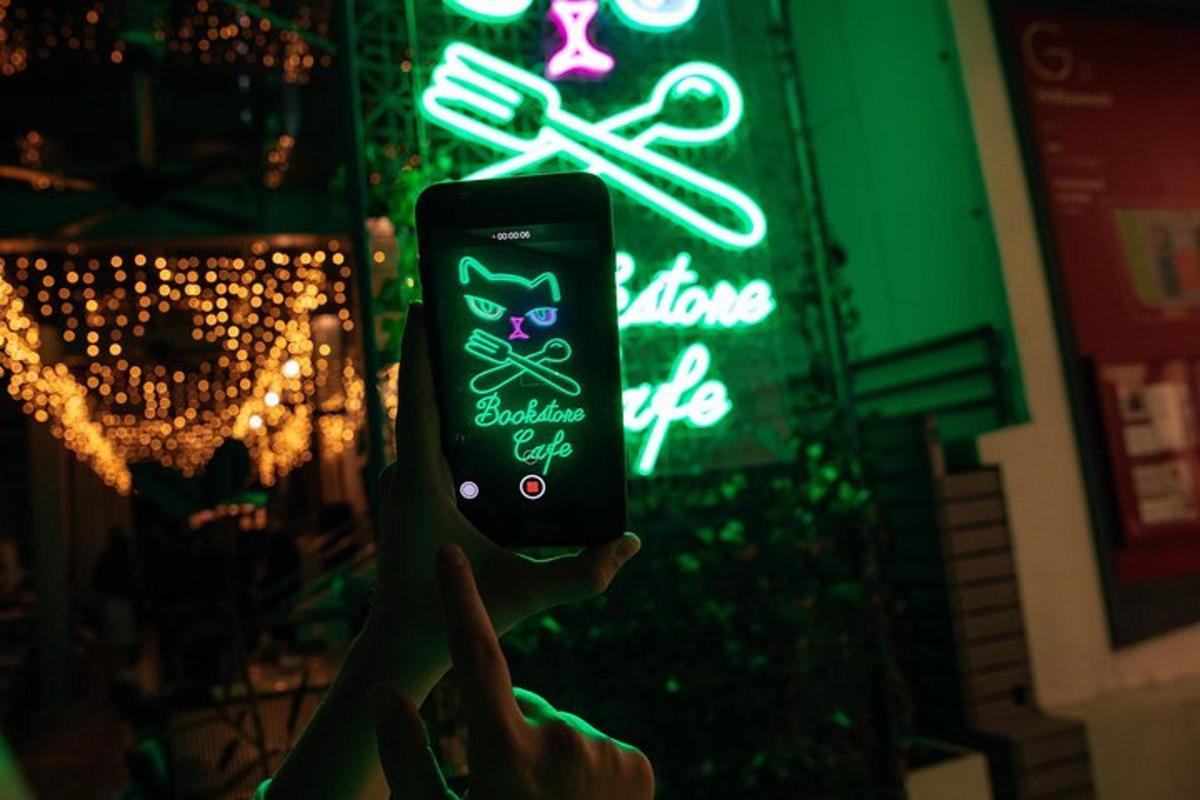 inimene hoiab neoonmärgi ees mobiiltelefoni