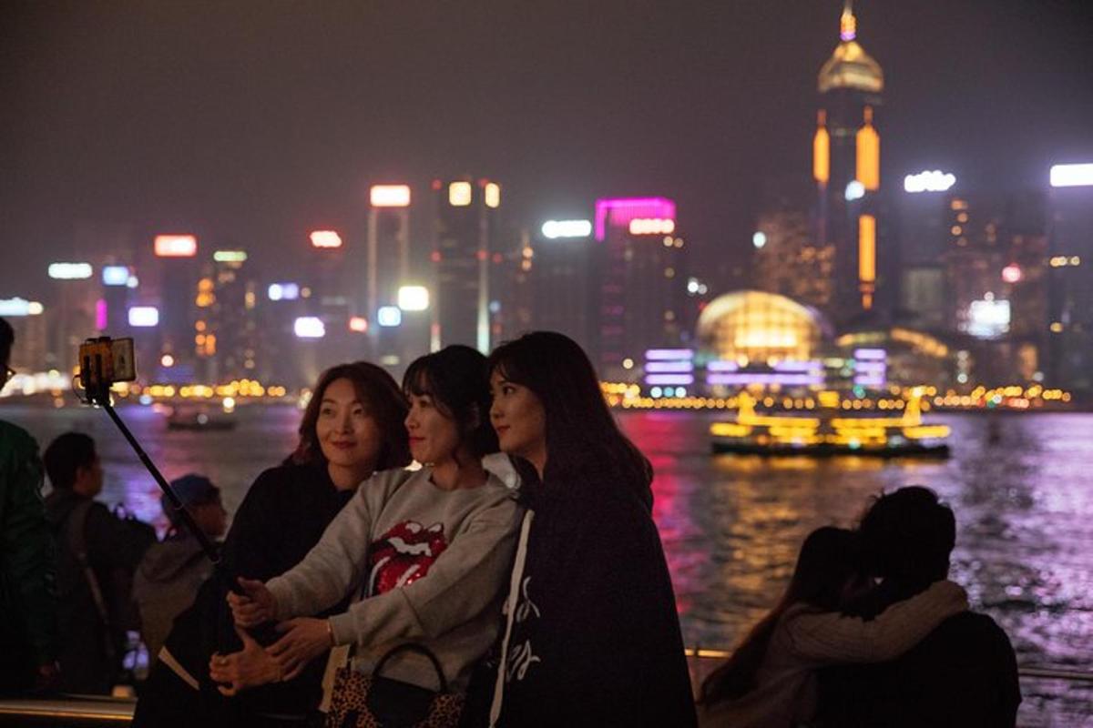 a group of women sitting next to the water at night