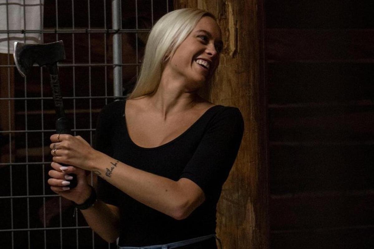 a woman is smiling while holding a hammer