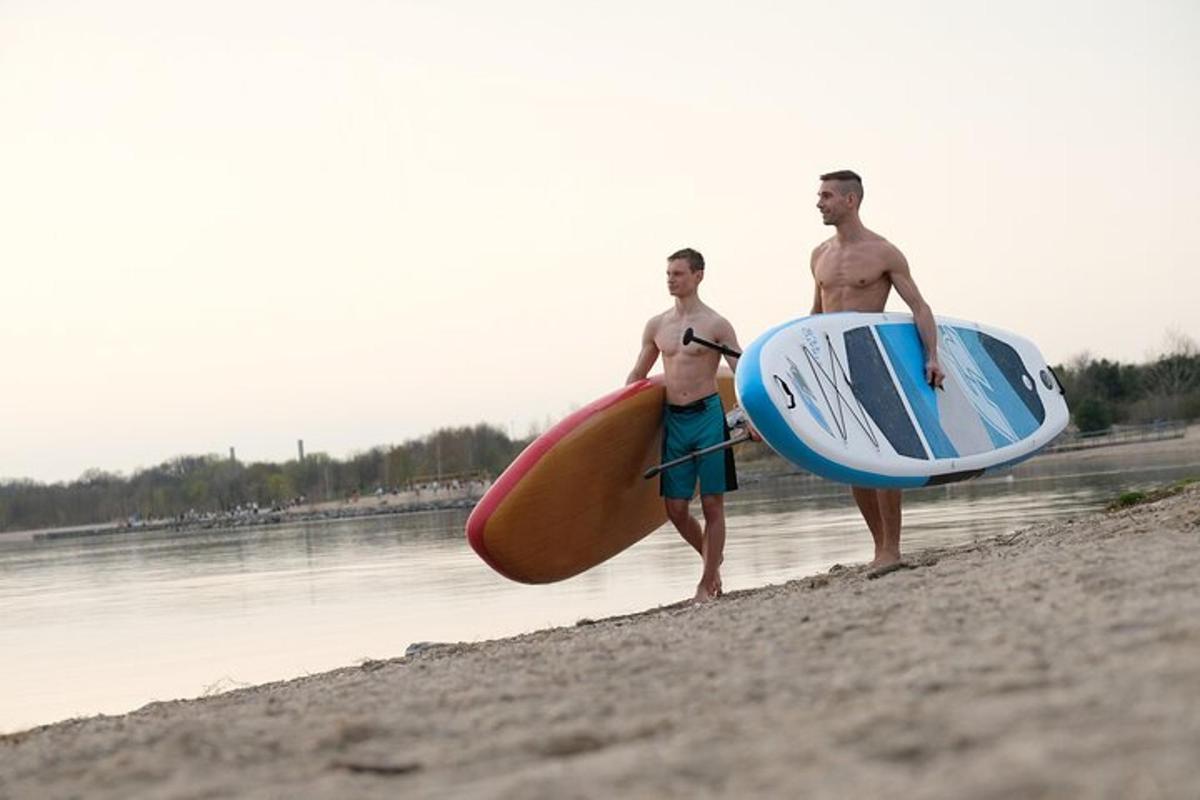 dwóch mężczyzn stojących na plaży z deskami surfingowymi