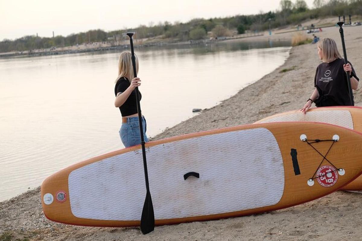 dwie kobiety stojące obok deski do pływania na plaży