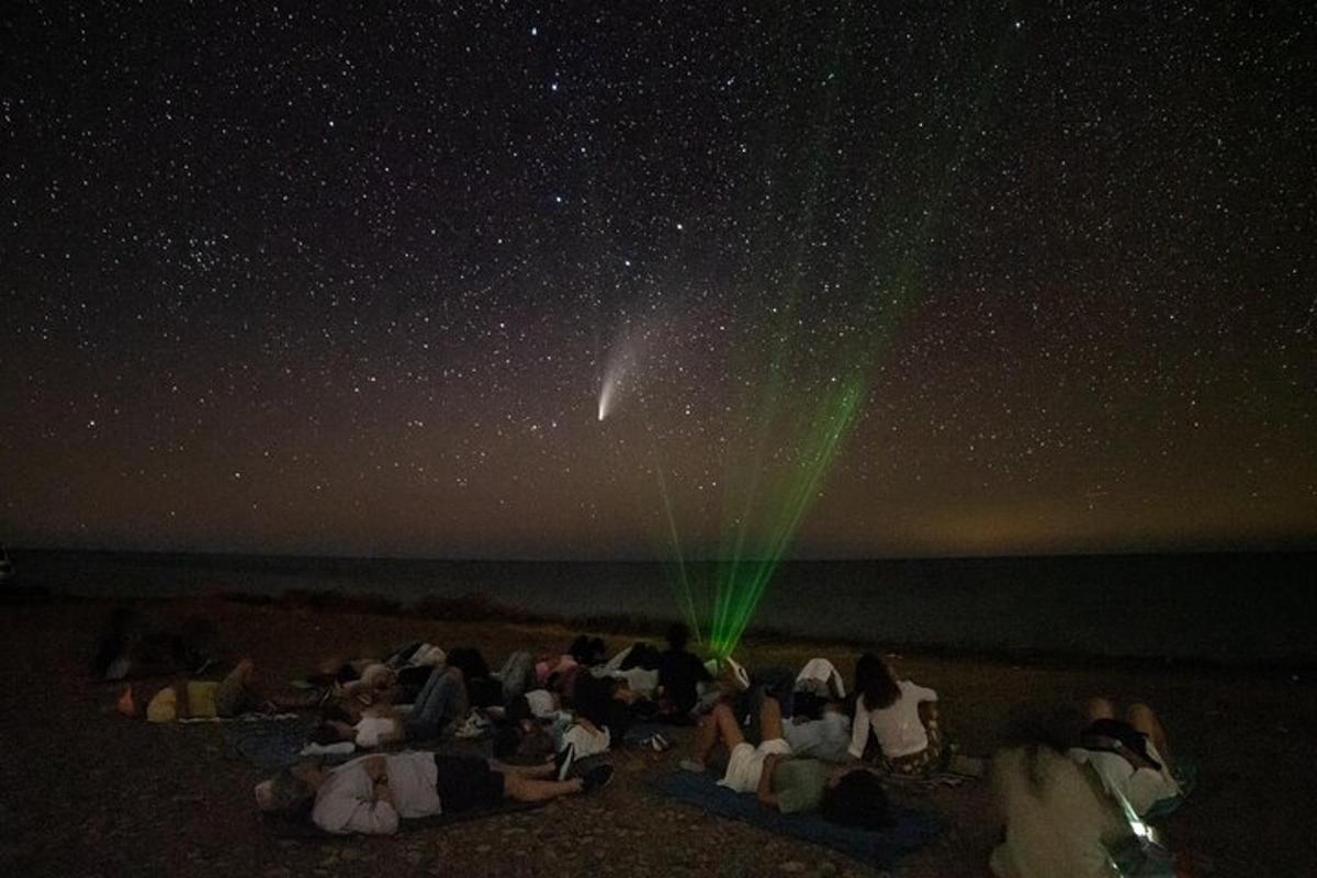 um grupo de pessoas sentadas na praia sob as estrelas