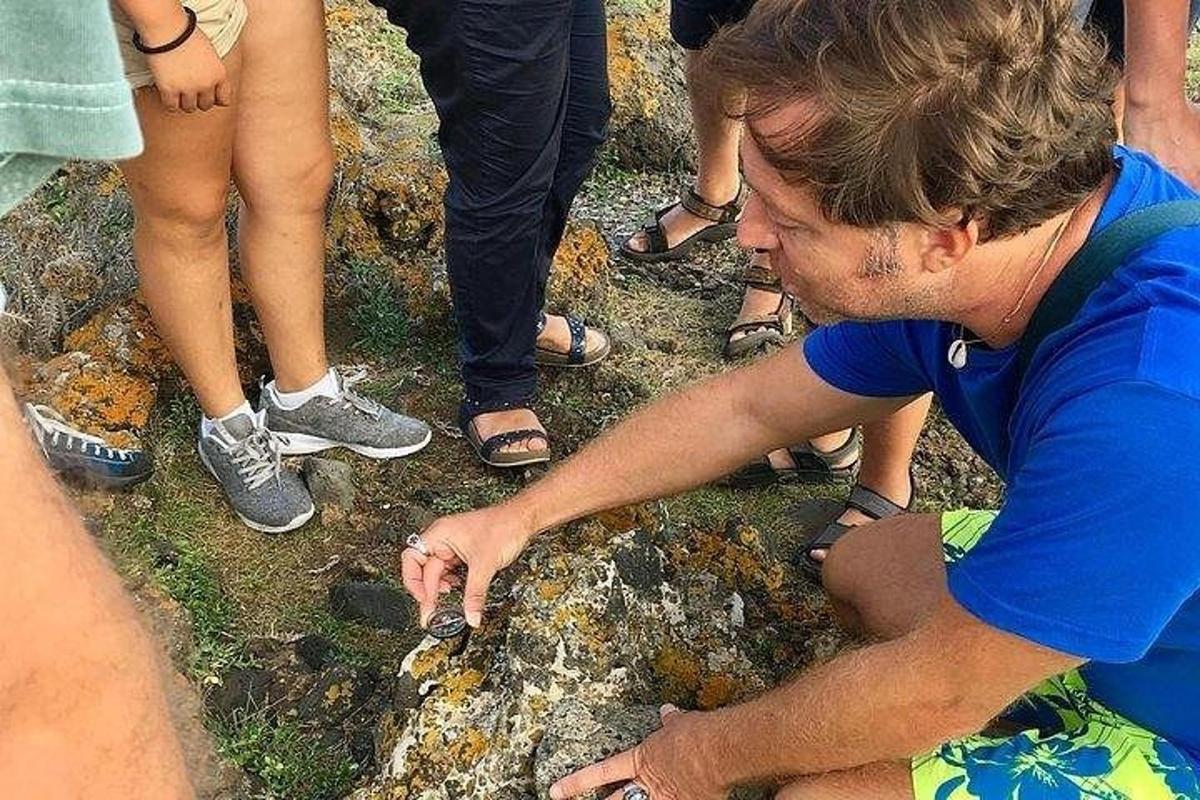 un home assegut a terra assenyalant una roca