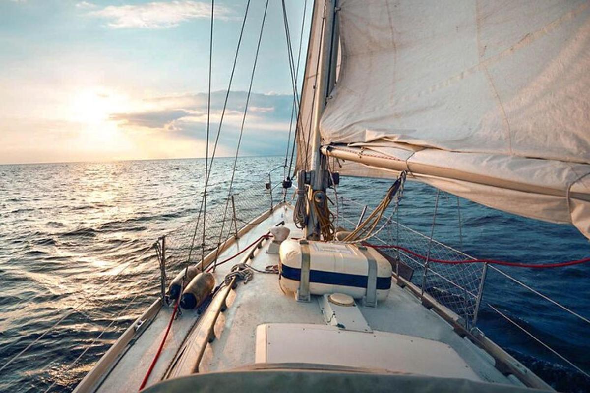 een zeilboot in de oceaan met de ondergaande zon