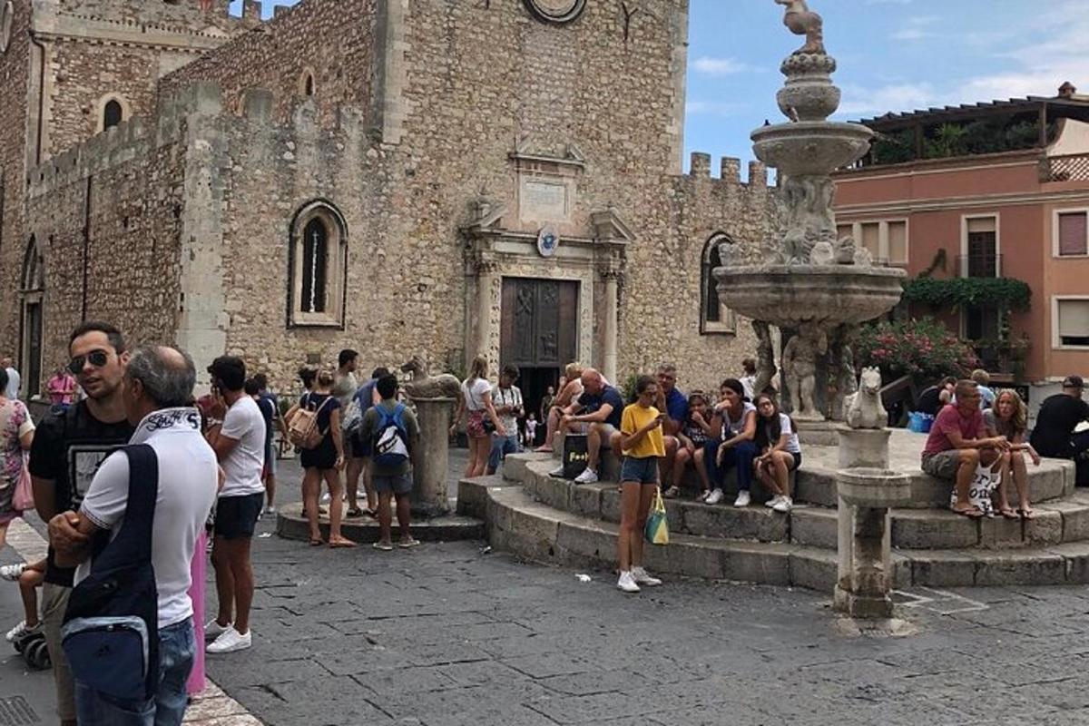un gruppo di persone in piedi attorno a una fontana di fronte a un edificio