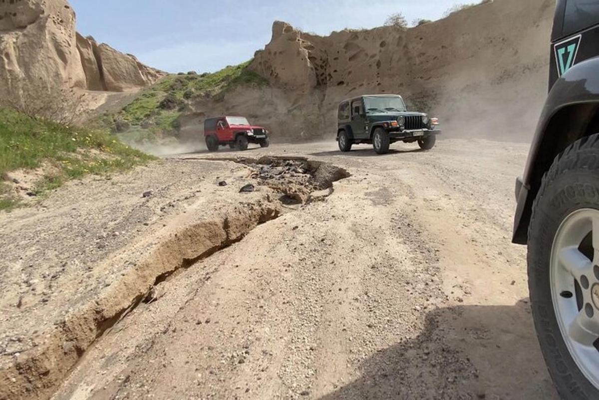 two trucks driving on a dirt road in the mountains
