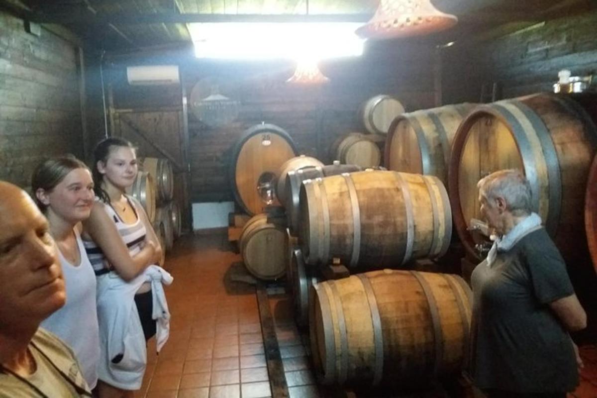 un gruppo di persone in piedi in una cantina con delle botti