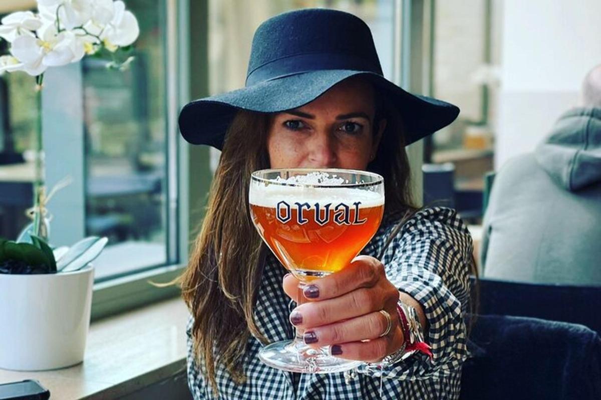 una donna che indossa un cappello e tiene in mano un bicchiere di birra