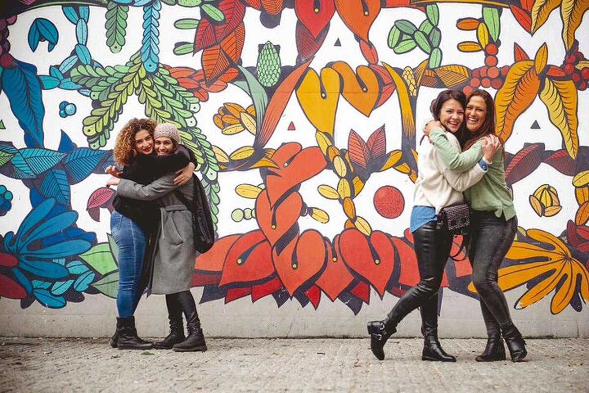 Tres mujeres están paradas frente a un mural.